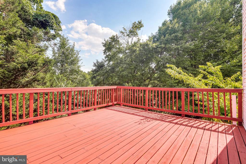 Red deck with matching railings overlooking a leafy wooded view.