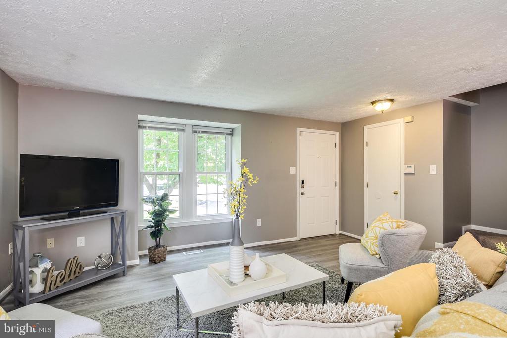 Furnished living room with two windows, a TV console, and yellow-accented seating.