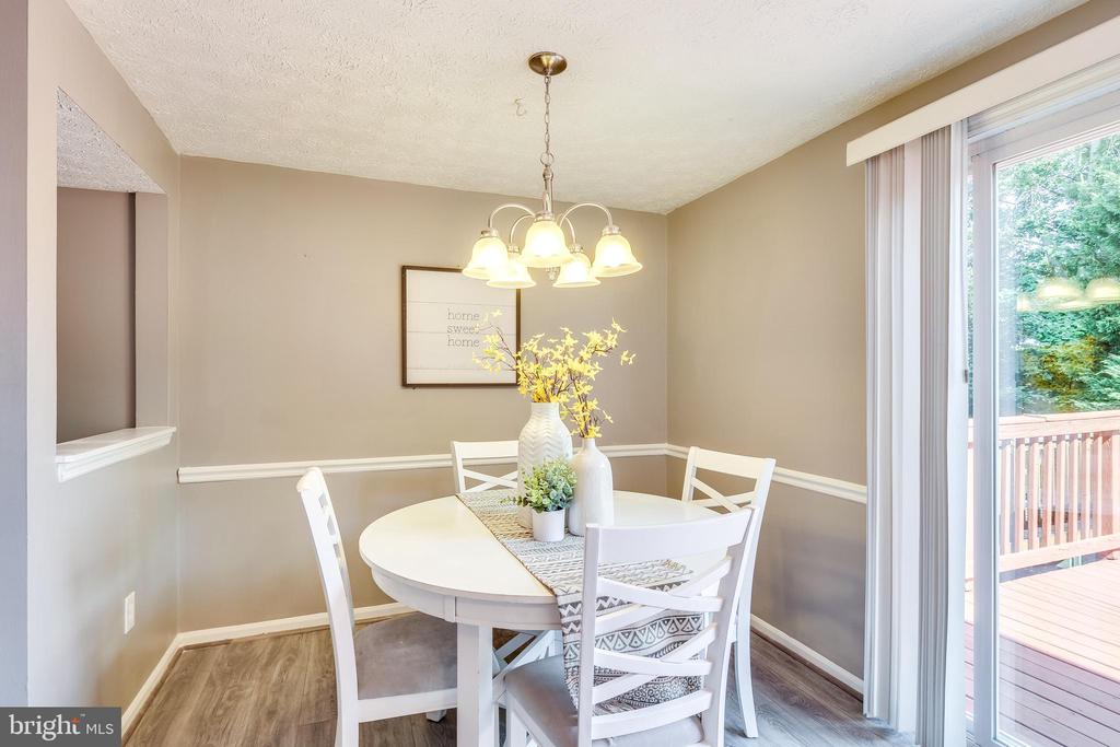 Dining room with a white oval table, chandelier, and sliding glass doors to a deck.