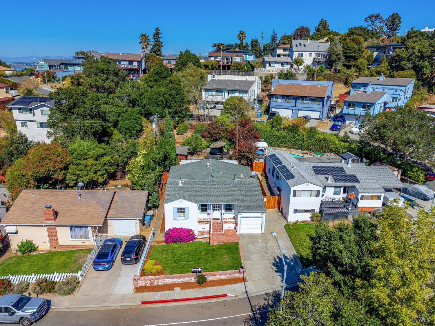 Aerial view of a white single-story home with a front lawn and brick walkway.
