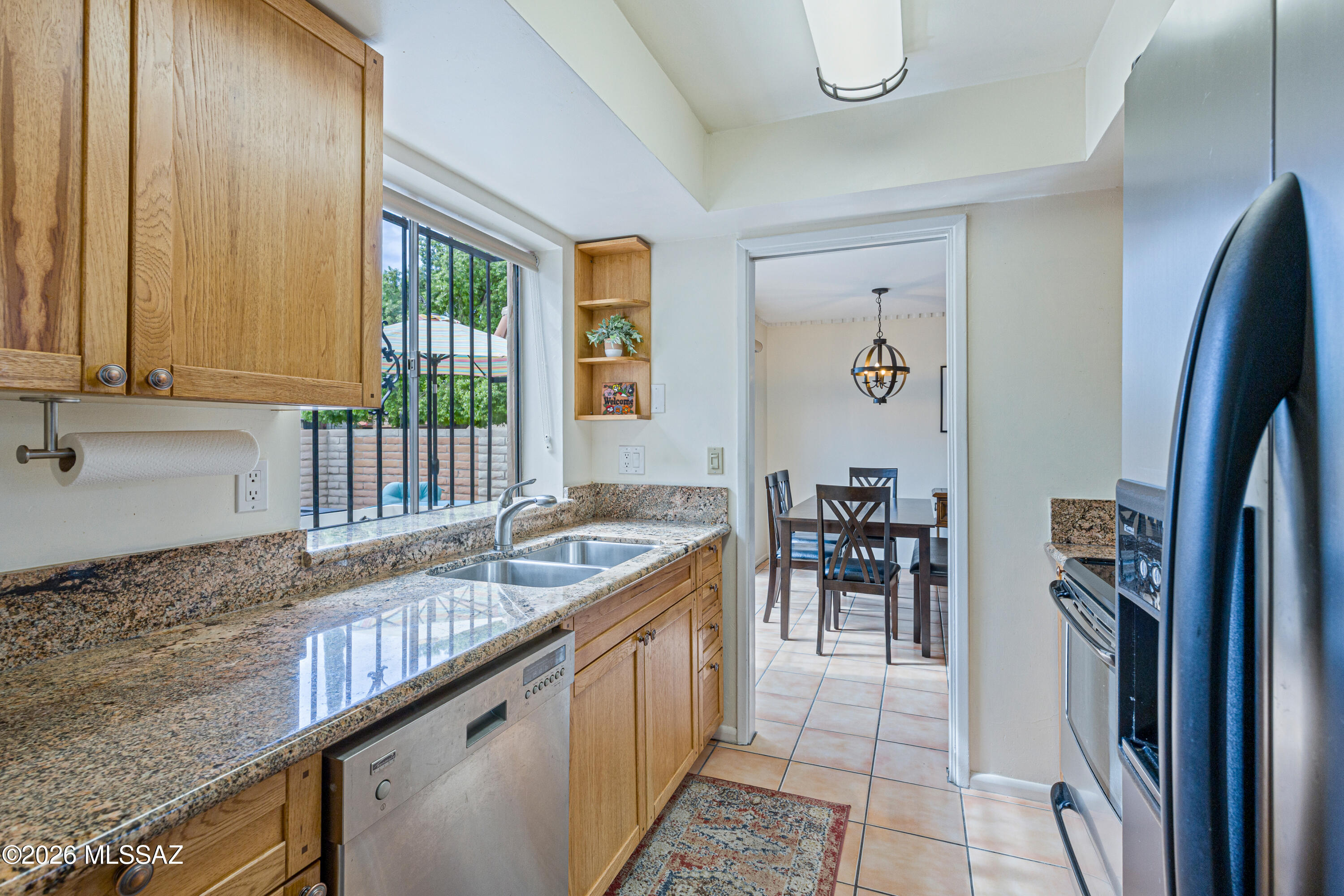 Kitchen with granite counters and oak cabinets, opening into a dining room.