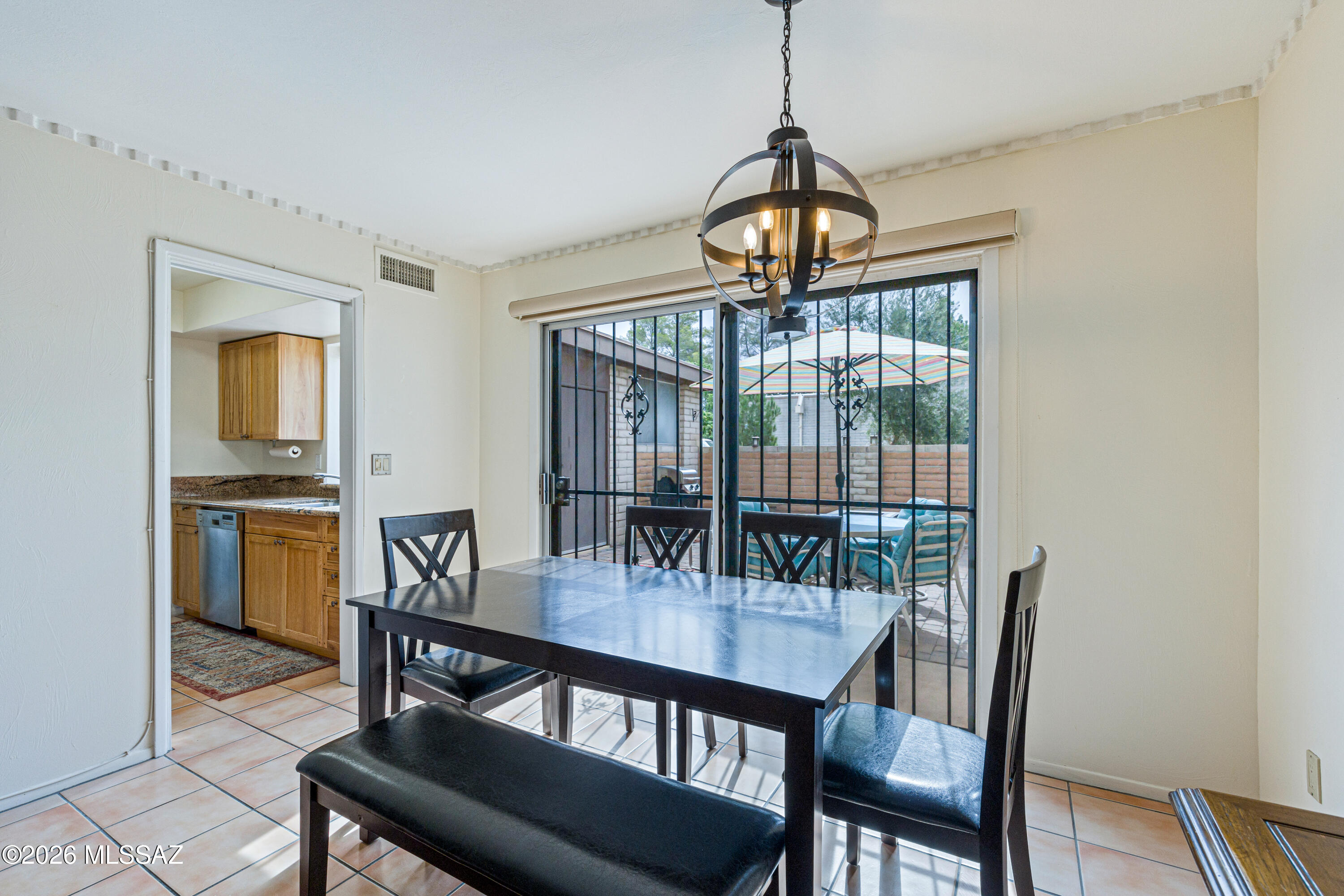 Dining room with a black table, chandelier, and sliding glass doors opening onto a covered patio.