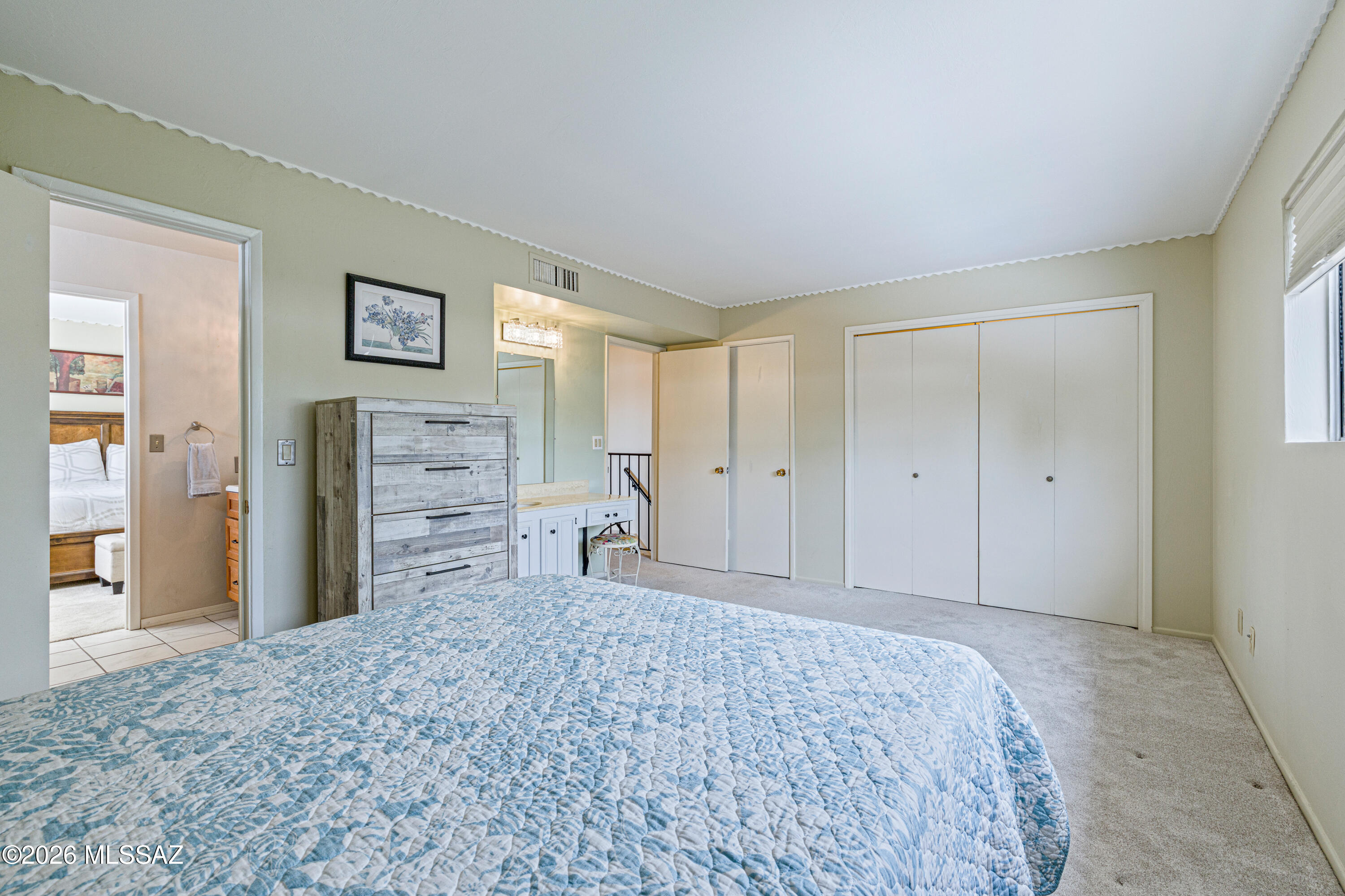 Bedroom with a blue-and-white quilted bed, weathered wood dresser, and wide white closet doors.