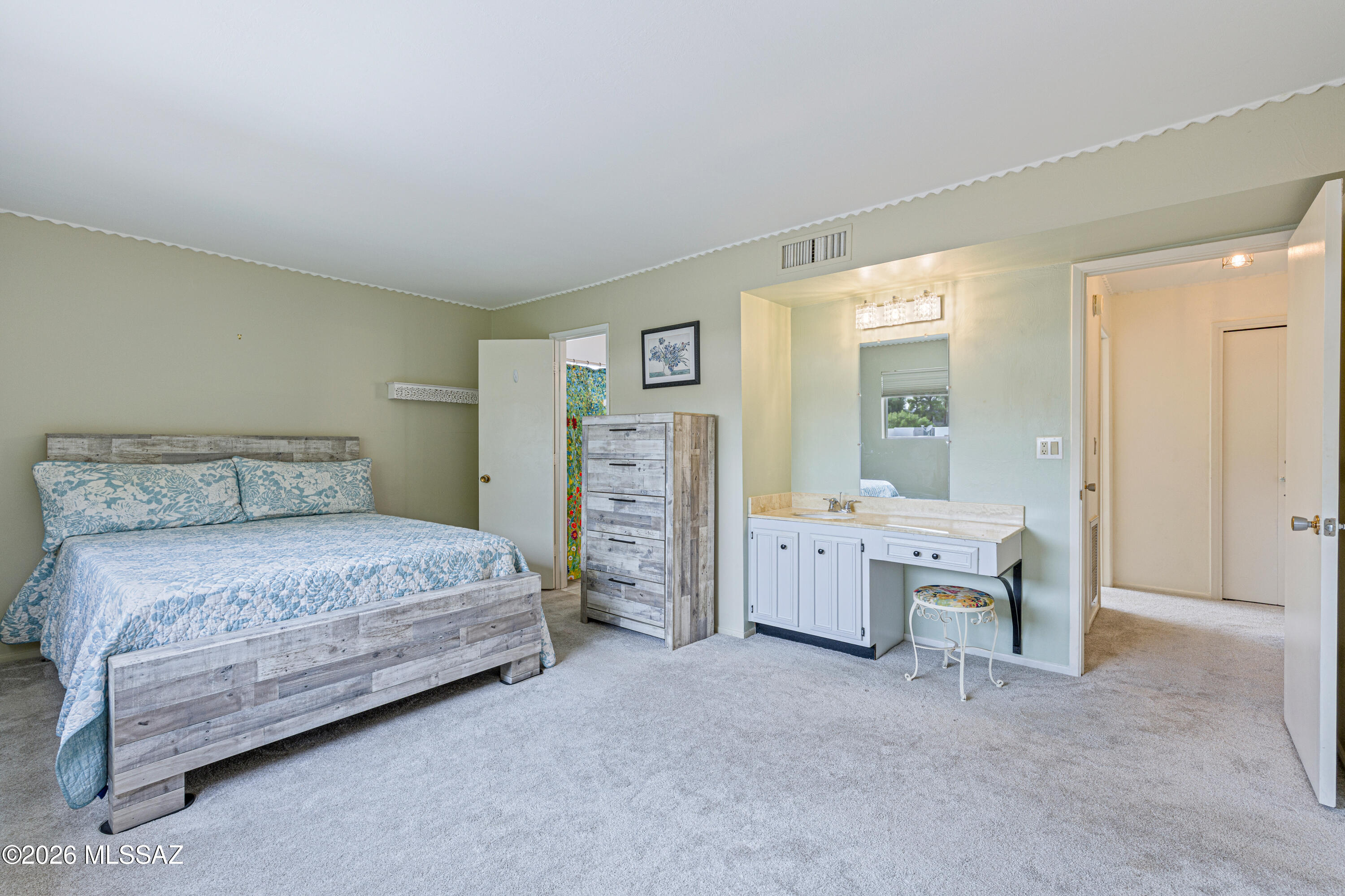 Bedroom with a weathered wood bed, blue patterned bedding, and a built-in vanity and mirror.