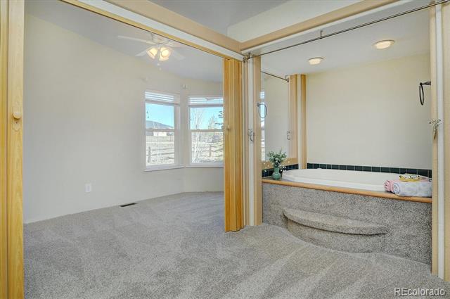 Carpeted bedroom adjoining a bathroom with a large built-in soaking tub.