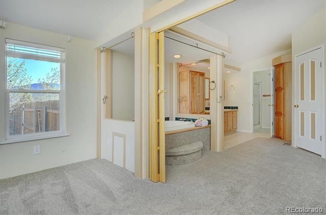 Carpeted bedroom opening to an en-suite bathroom with a built-in tub and wood cabinetry.