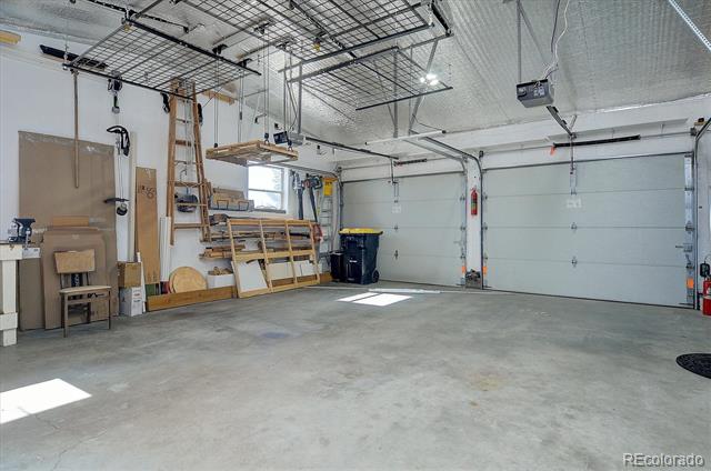 Spacious garage with two sectional doors, overhead storage racks, and workshop shelving along one wall.