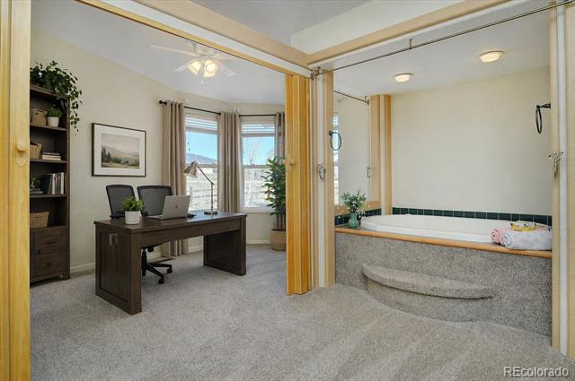 Home office beside a raised soaking tub and tiled shower area.