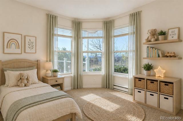 Staged bedroom with a wooden bed, teddy bear, and three tall curtained windows.