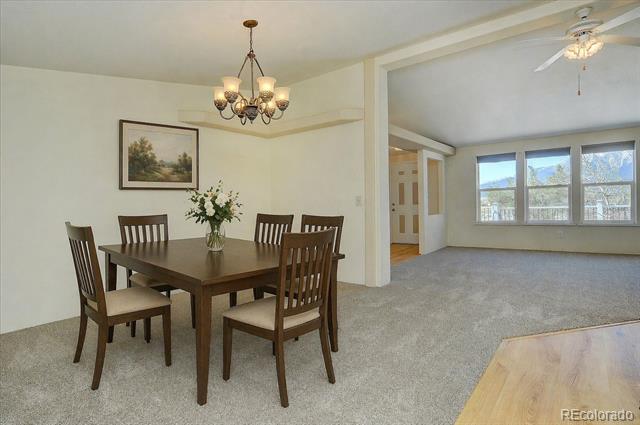 Dining area with a dark wood table and chandelier beside a bright living room.