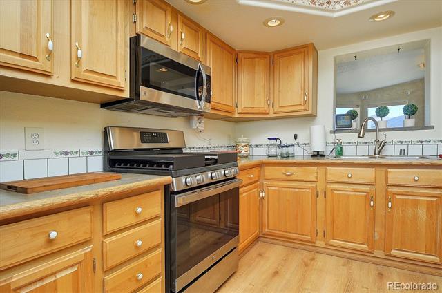 Kitchen with honey-colored cabinets, stainless steel appliances, and a window above the sink.