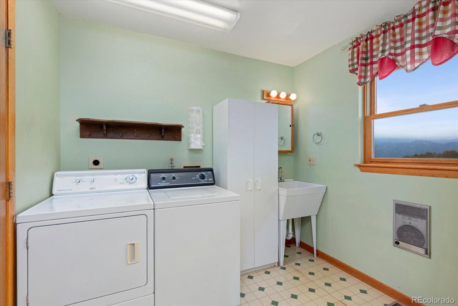 Laundry room with washer, dryer, utility sink, and a window overlooking distant mountains.