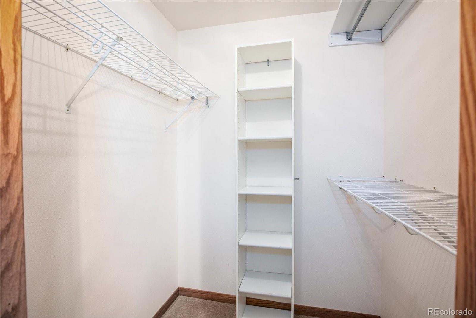 Walk-in closet with wire shelves on two walls and a tall built-in shelving unit.