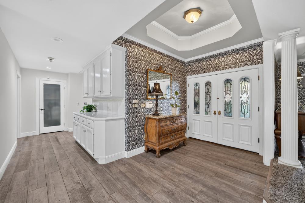 Entry foyer with patterned wallpaper, glass-paneled double doors, and white built-in cabinetry.