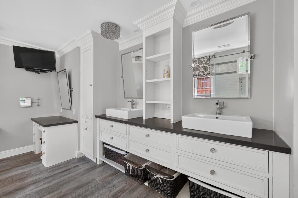 Bathroom with a long double vanity, vessel sinks, dark countertop, and woven storage baskets.