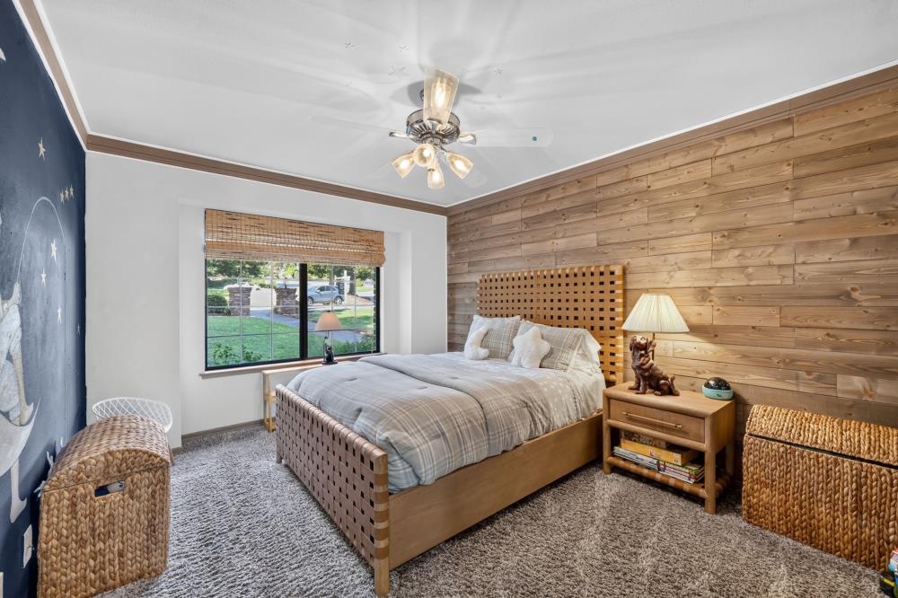 Bedroom with a wood-plank accent wall, gray bedding, and woven storage baskets.