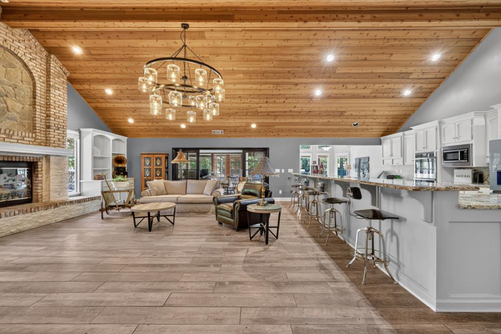 Open-plan living room and kitchen with a vaulted wood ceiling and stone fireplace
