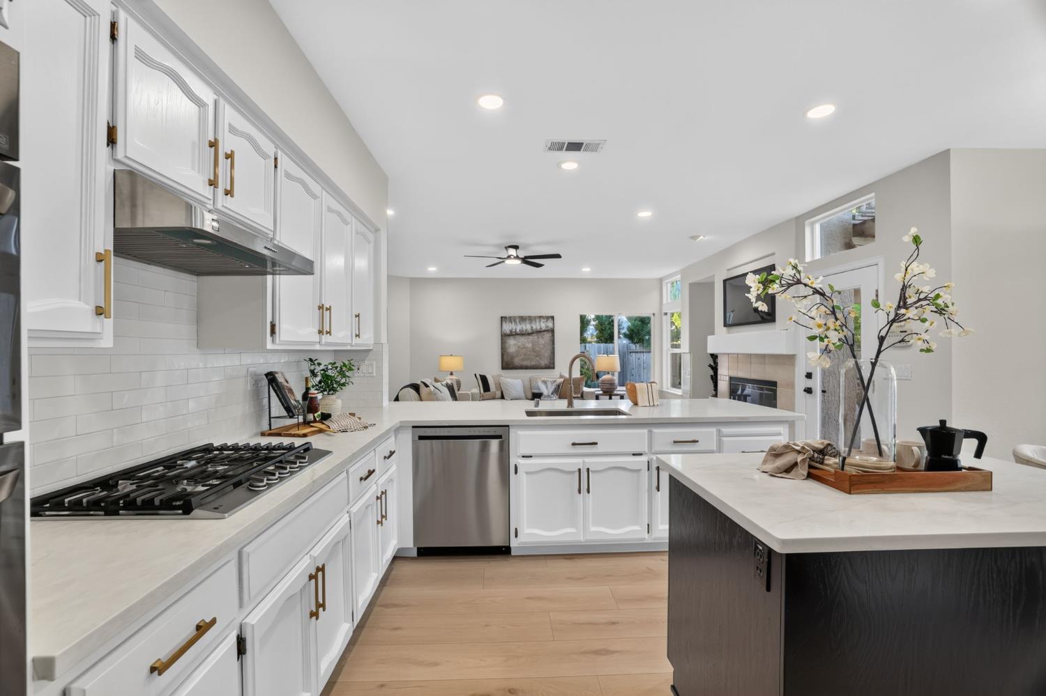 Open-plan kitchen with white cabinets, stainless appliances, and a large island overlooking the living room.