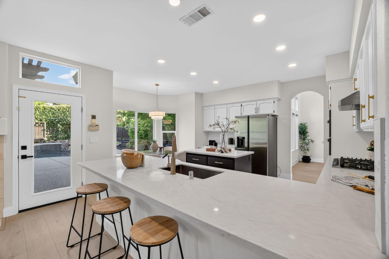 Open kitchen with a large white island, stainless appliances, and a glass door to the backyard patio.