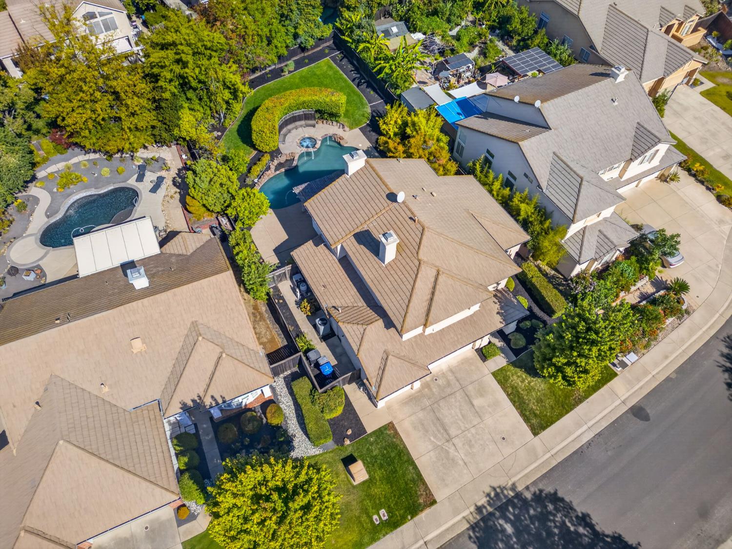 Aerial view of a home with a landscaped yard and curved swimming pool.