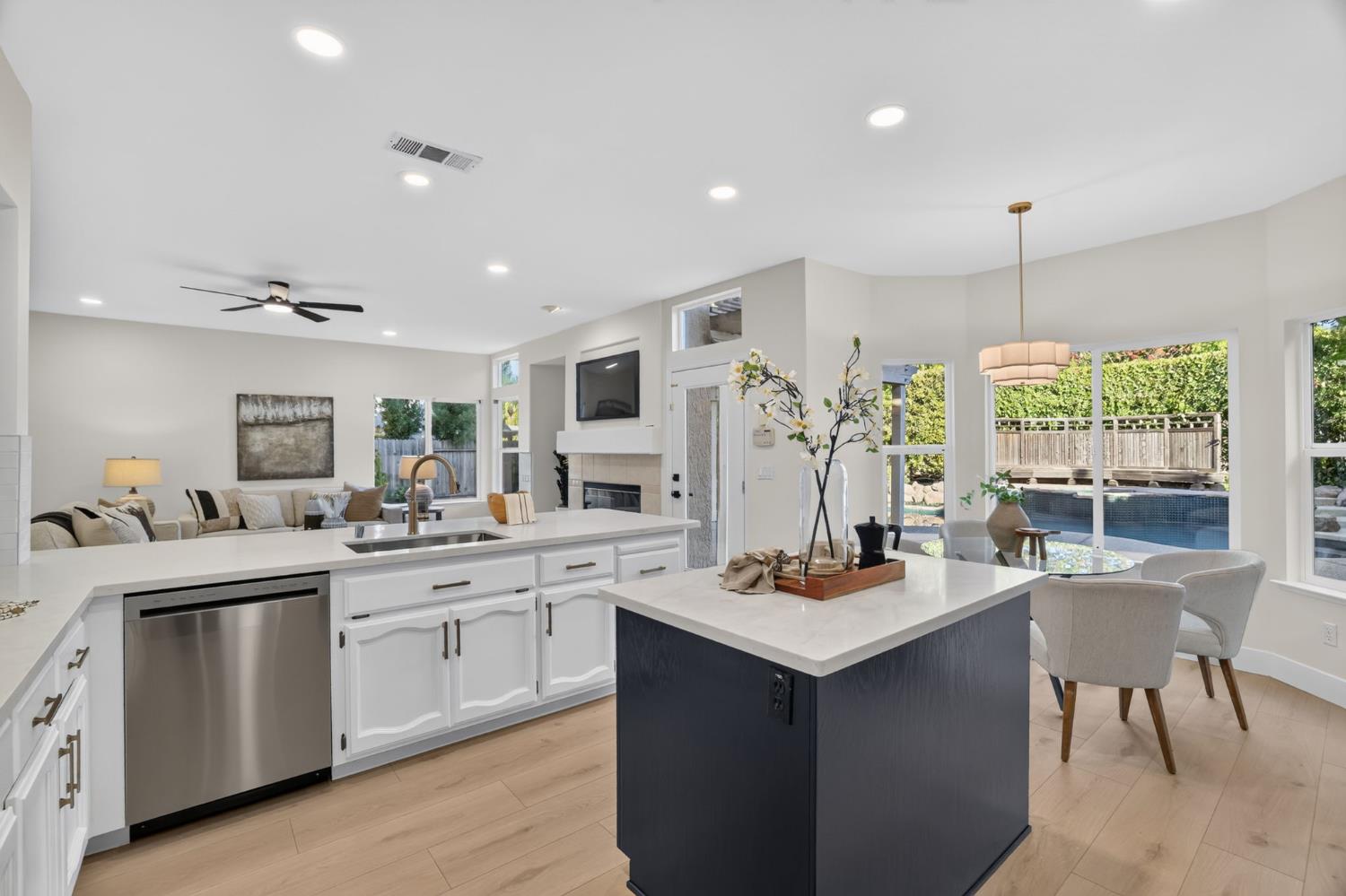 Open-plan kitchen with a dark blue island and pool visible through the windows.