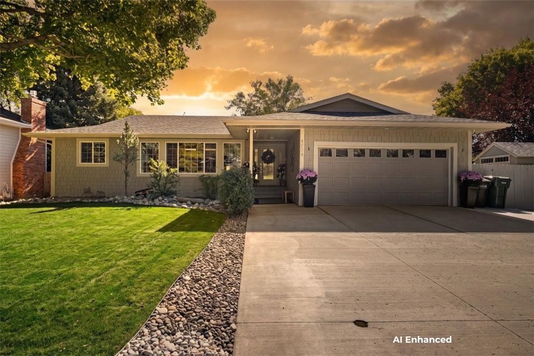 Single-story home with a two-car garage, landscaped lawn, and rock garden at sunset.