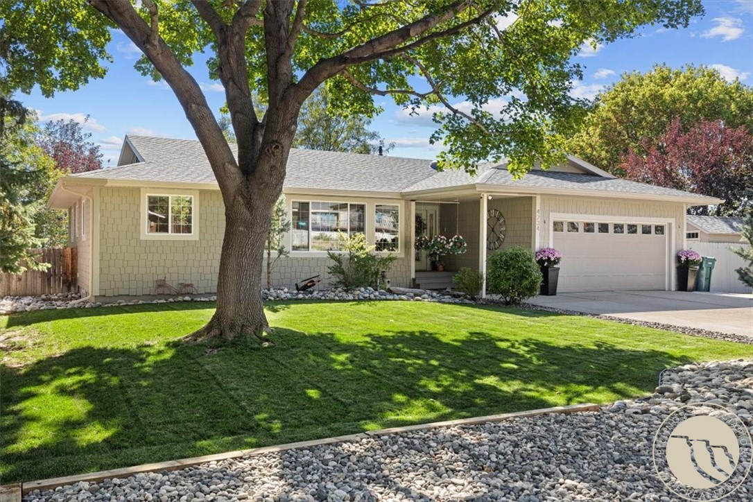 Single-story home with an attached garage behind a large shade tree and landscaped lawn.