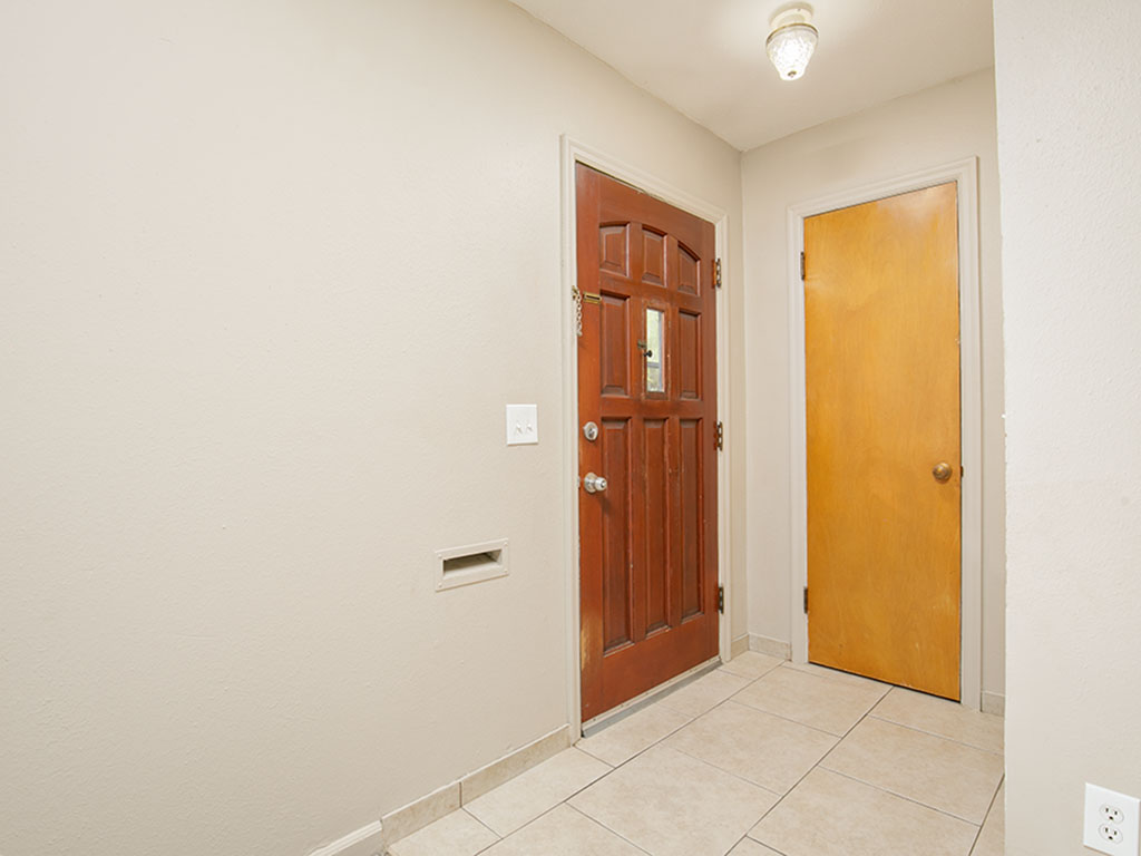 Entryway with a dark paneled front door, a second honey-colored door, and light tile flooring.