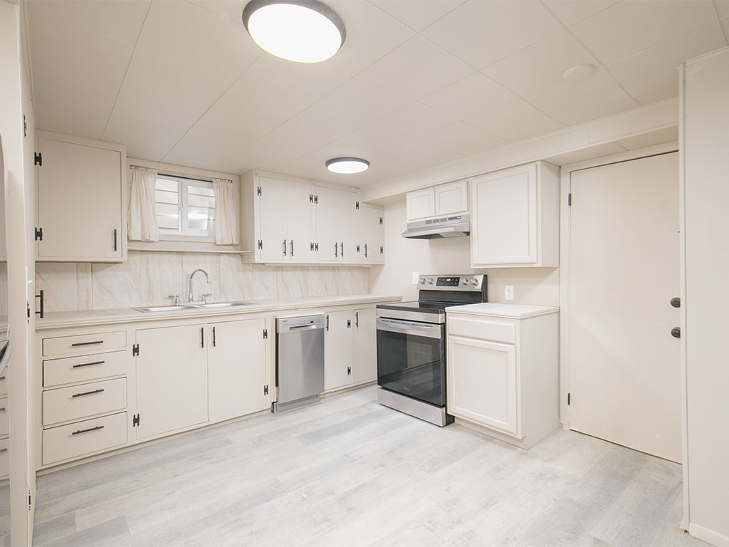 Kitchen with white cabinets, stainless-steel appliances, and a small window above the sink.