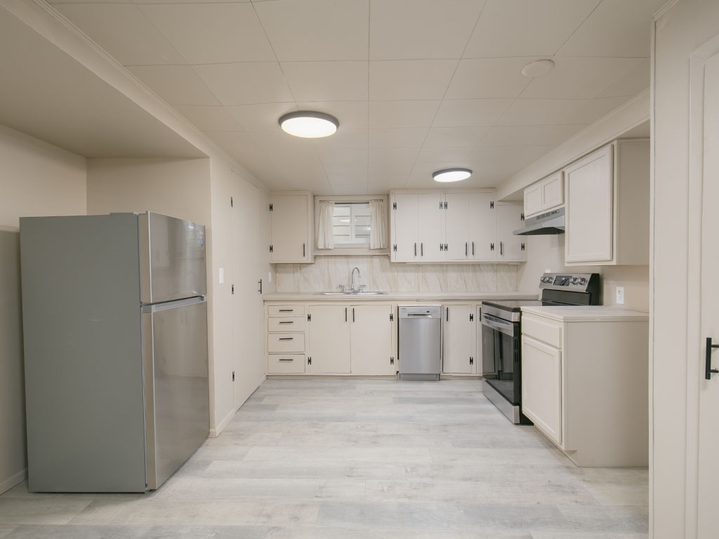 Kitchen with white cabinetry, pale flooring, stainless steel appliances, and a small window above the sink.
