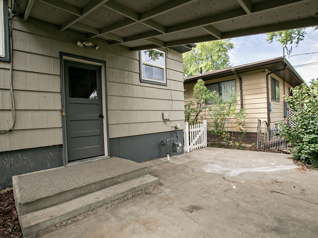Home exterior with a covered carport, concrete driveway, and side entrance.