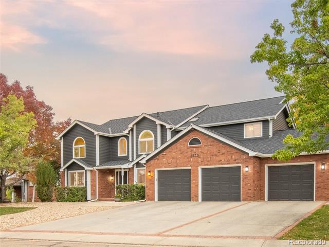 Two-story gray-and-brick home with arched windows and a three-car garage.