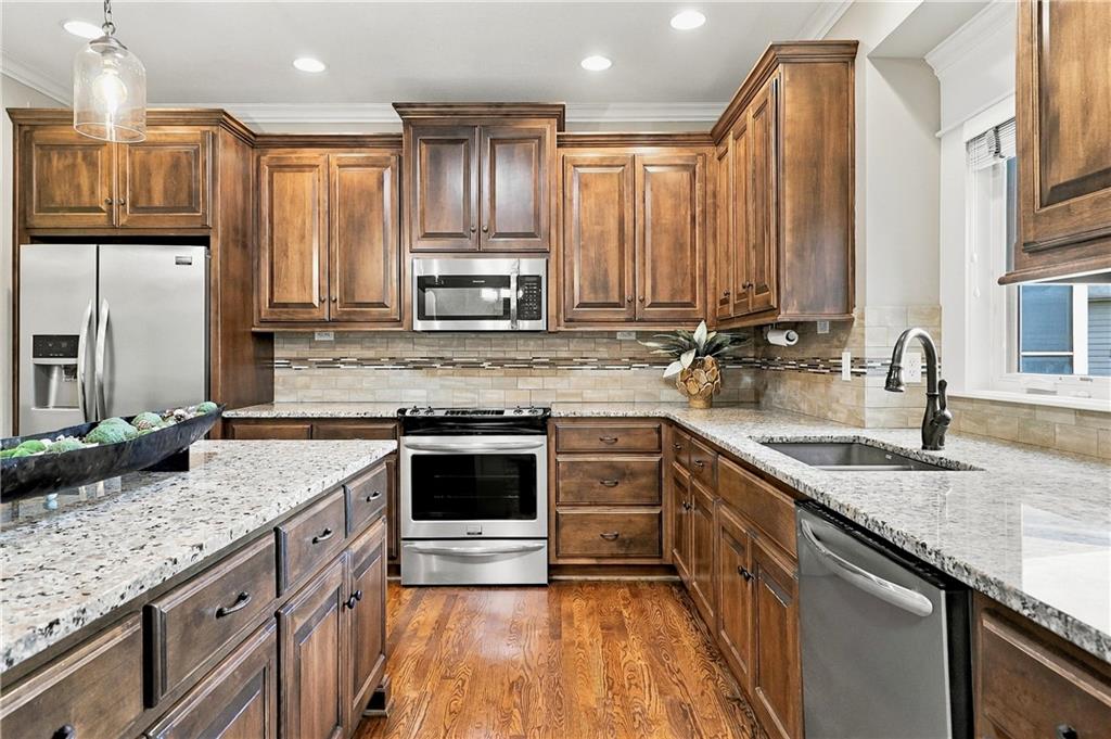 Kitchen with rich wood cabinets, granite counters, stainless steel appliances, and hardwood floors.