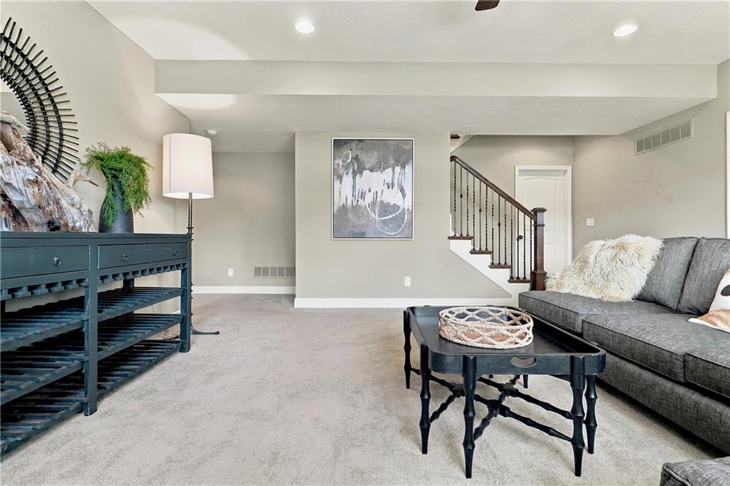 Furnished living room with a charcoal sofa, black coffee table, and staircase with dark railing.