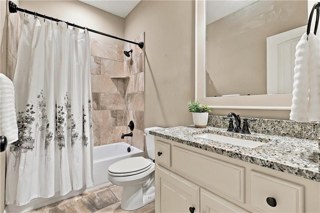 Bathroom with granite vanity, large mirror, and tiled tub surround behind a floral shower curtain.