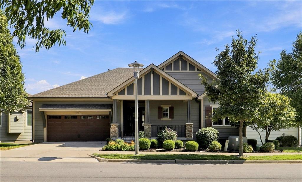 Gray-sided home with a double garage, covered porch, and landscaped front yard.
