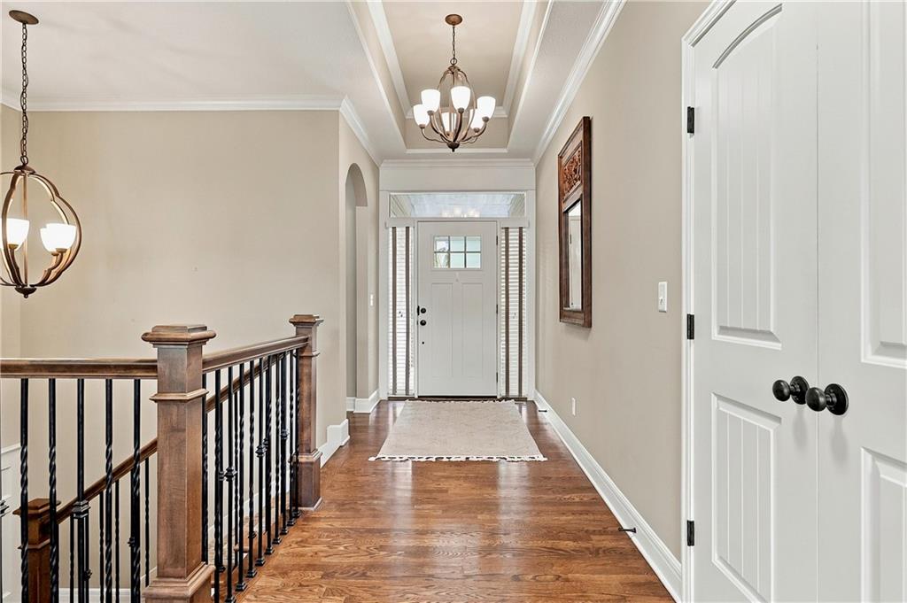 Upstairs entry hall with hardwood floors, a dark stair railing, and a white front door.