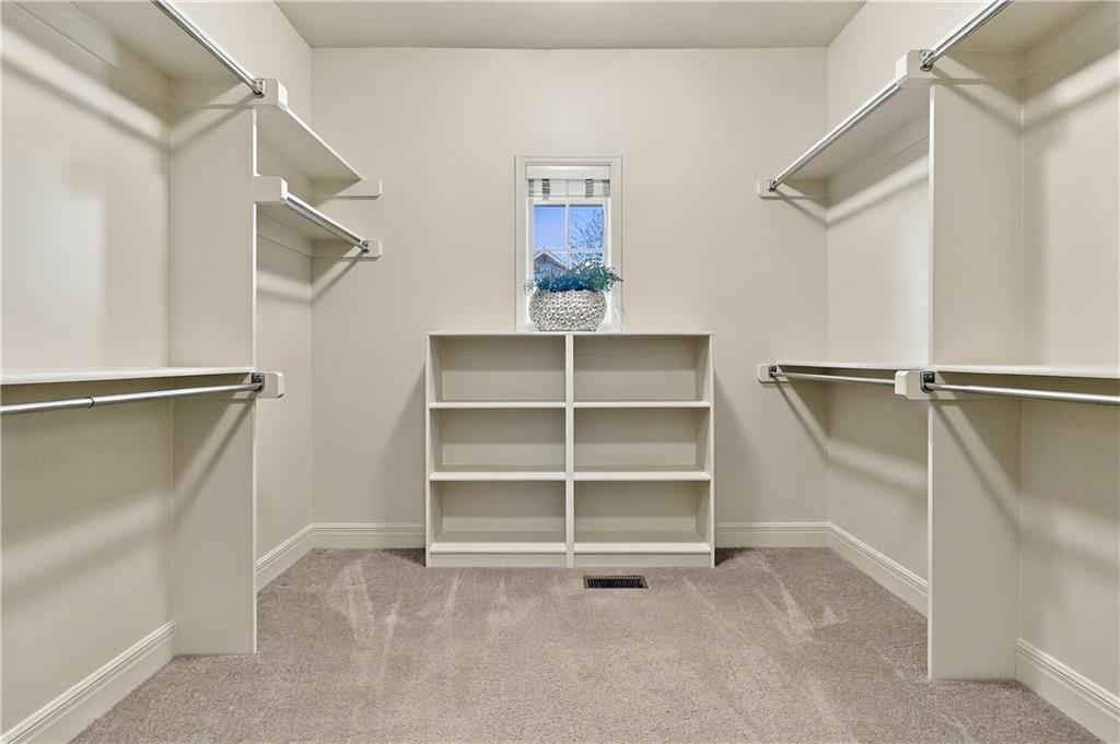 Walk-in closet with built-in hanging rods, central cubby shelves, and a small window.