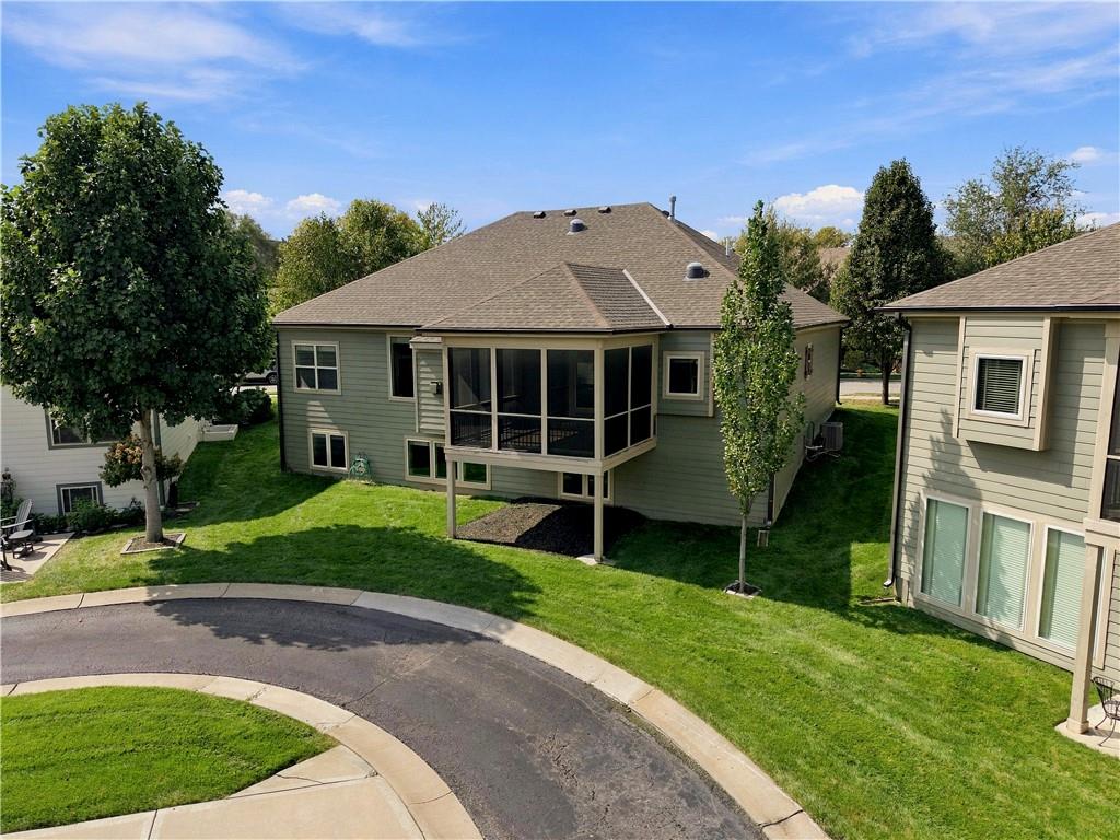 Rear of a light-green house with a raised screened porch and broad lawn.