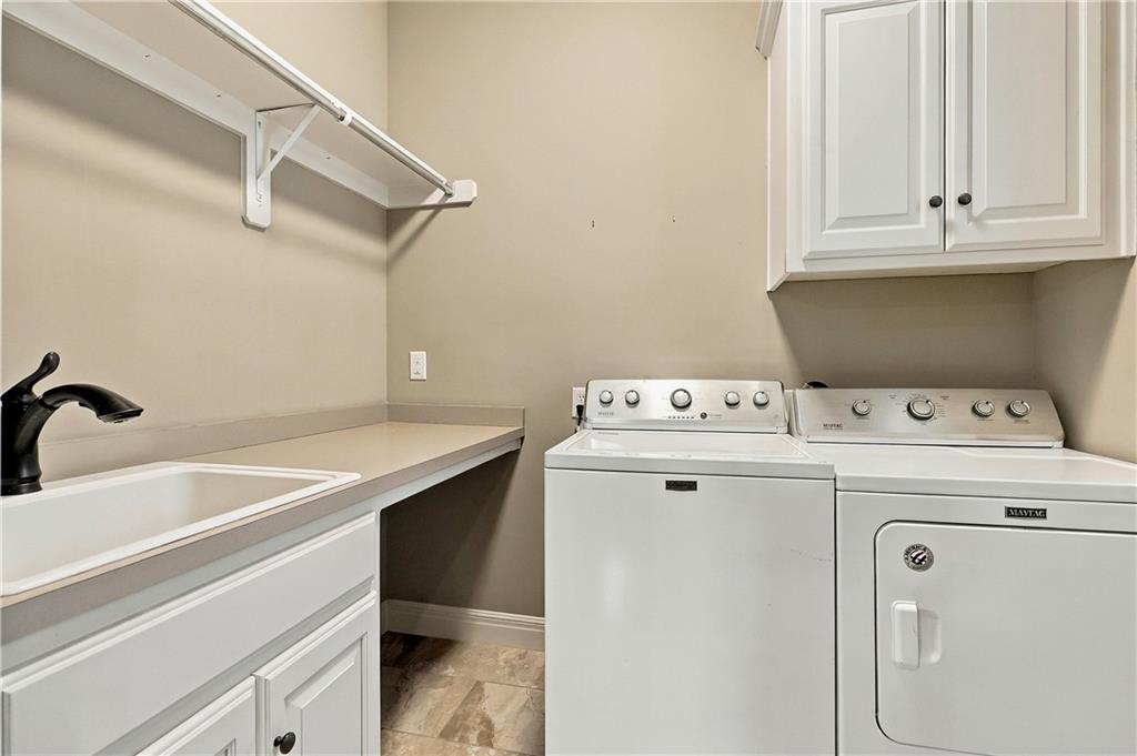 Laundry room with washer, Maytag dryer, utility sink, counter, and overhead cabinets.