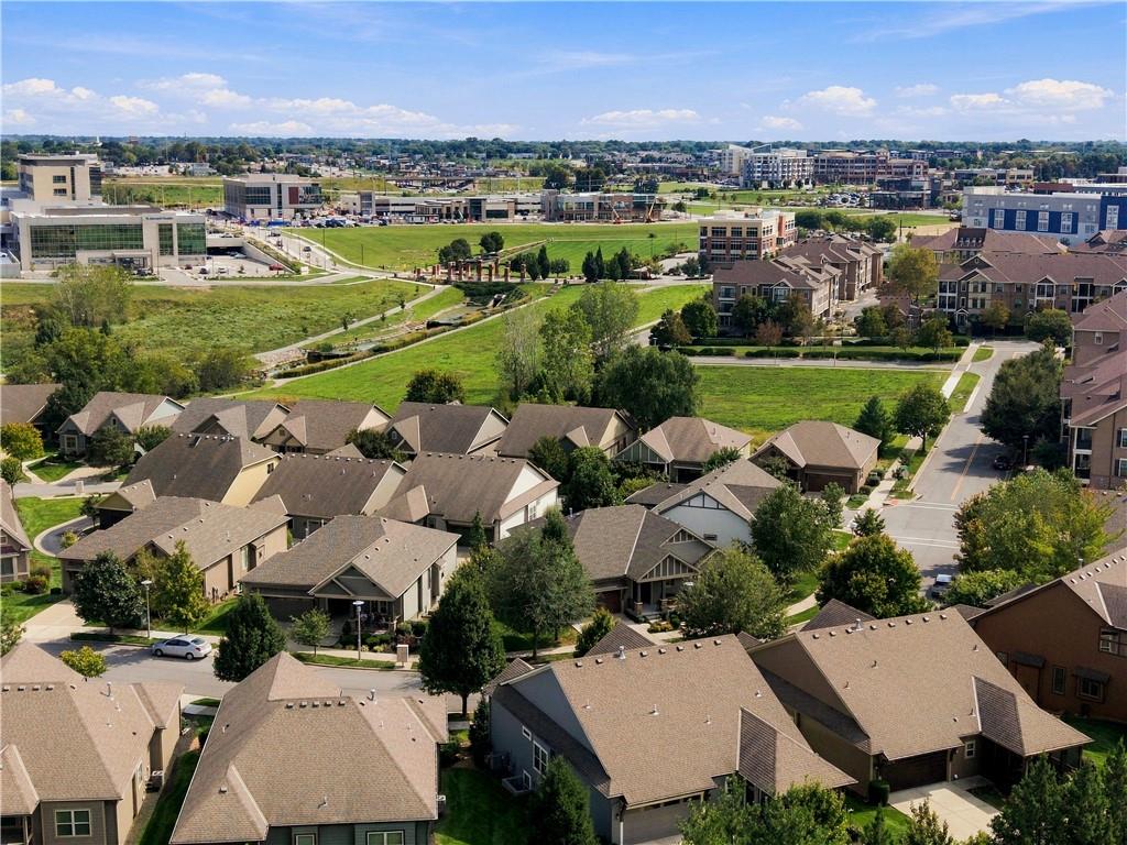 Aerial view of a residential neighborhood with a green corridor and commercial buildings beyond.