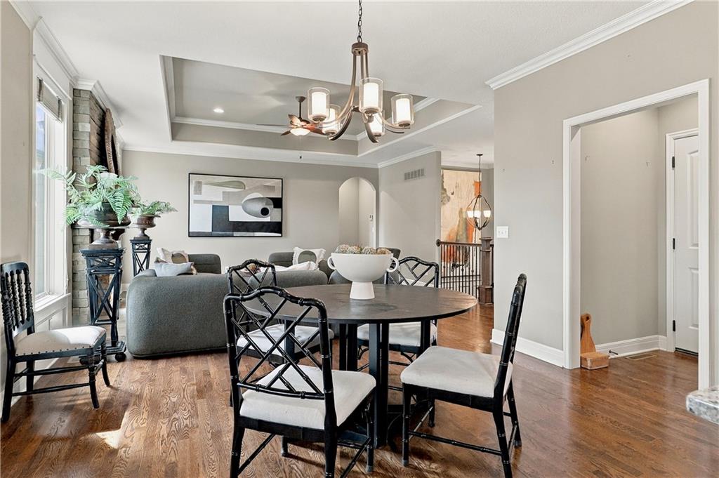 Dining room with a round table and chandelier adjoining a living area with a gray sofa.