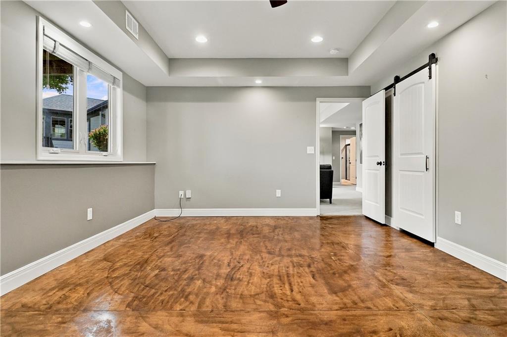 Empty room with warm-toned flooring, a large window, and white barn-style doors.