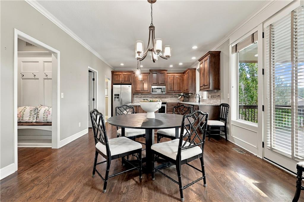 Dining area with a round table and chandelier, opening onto a dark wood kitchen.