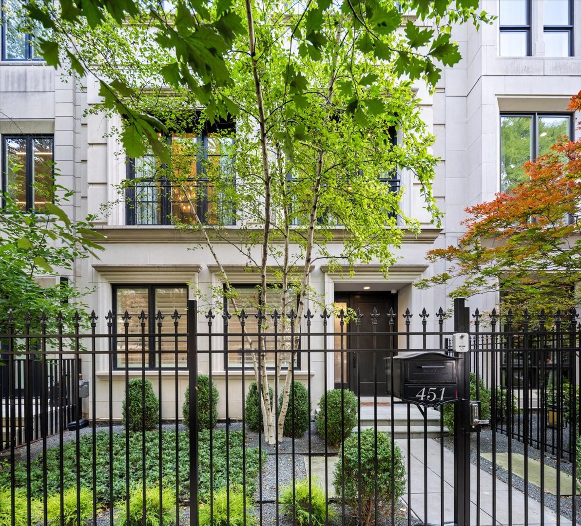 451 W Deming Place’s light stone facade and gated, landscaped entrance beneath leafy trees.