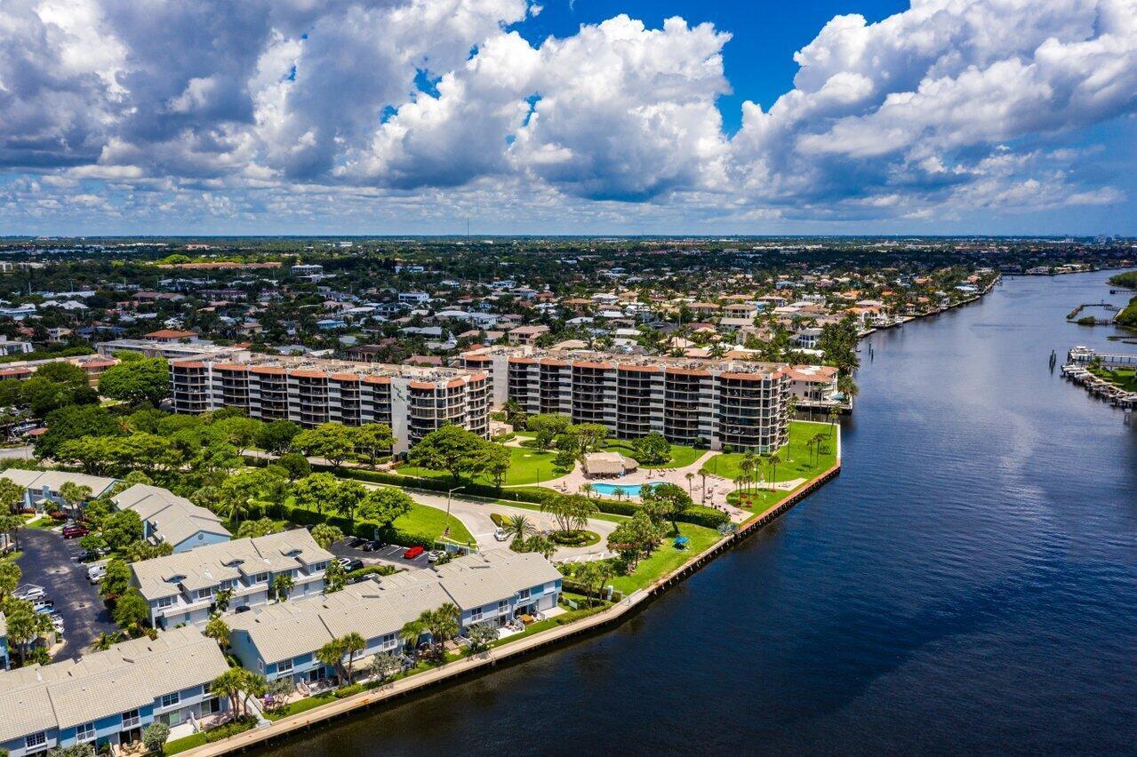 Waterfront condominiums and homes line a canal, with a pool and landscaped grounds.