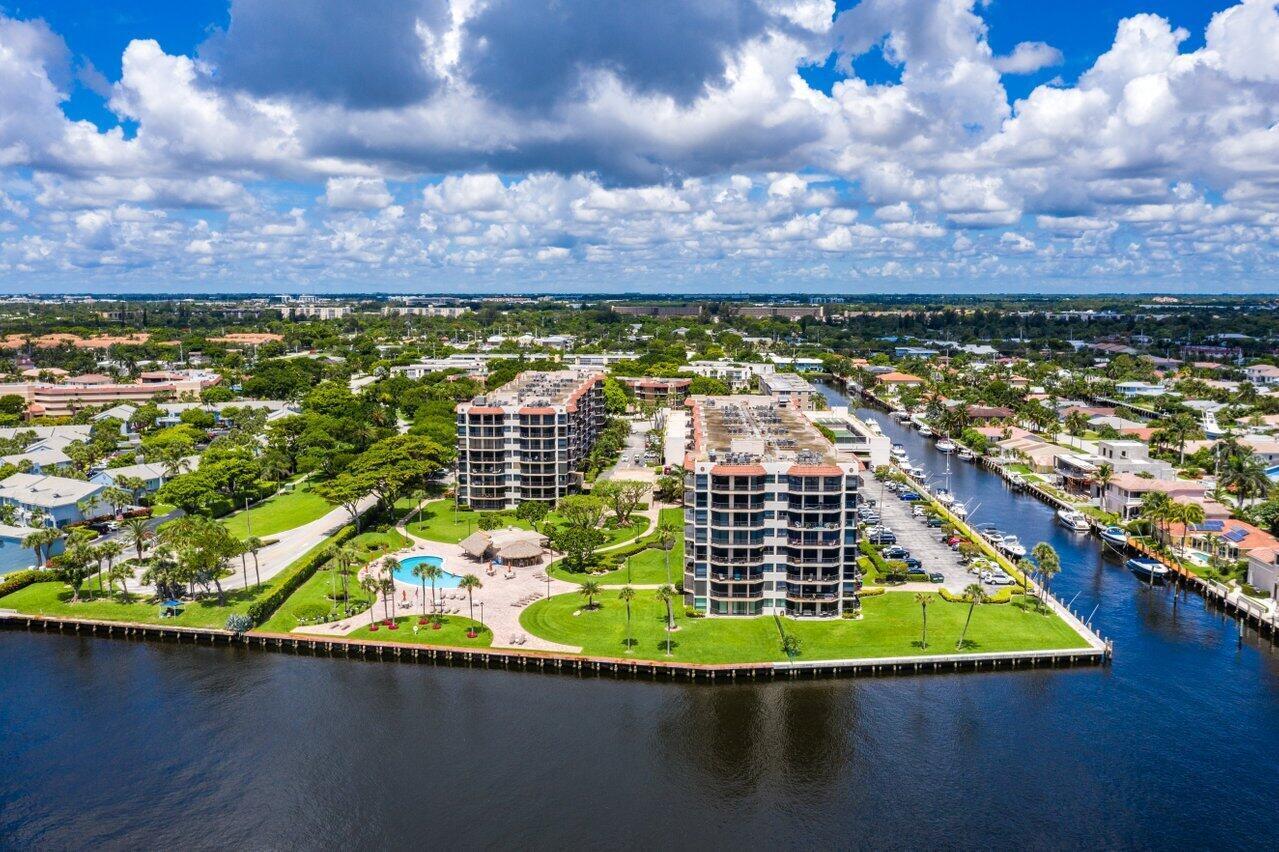 Waterfront condominium complex with a canal, boats, and a pool, viewed from above.