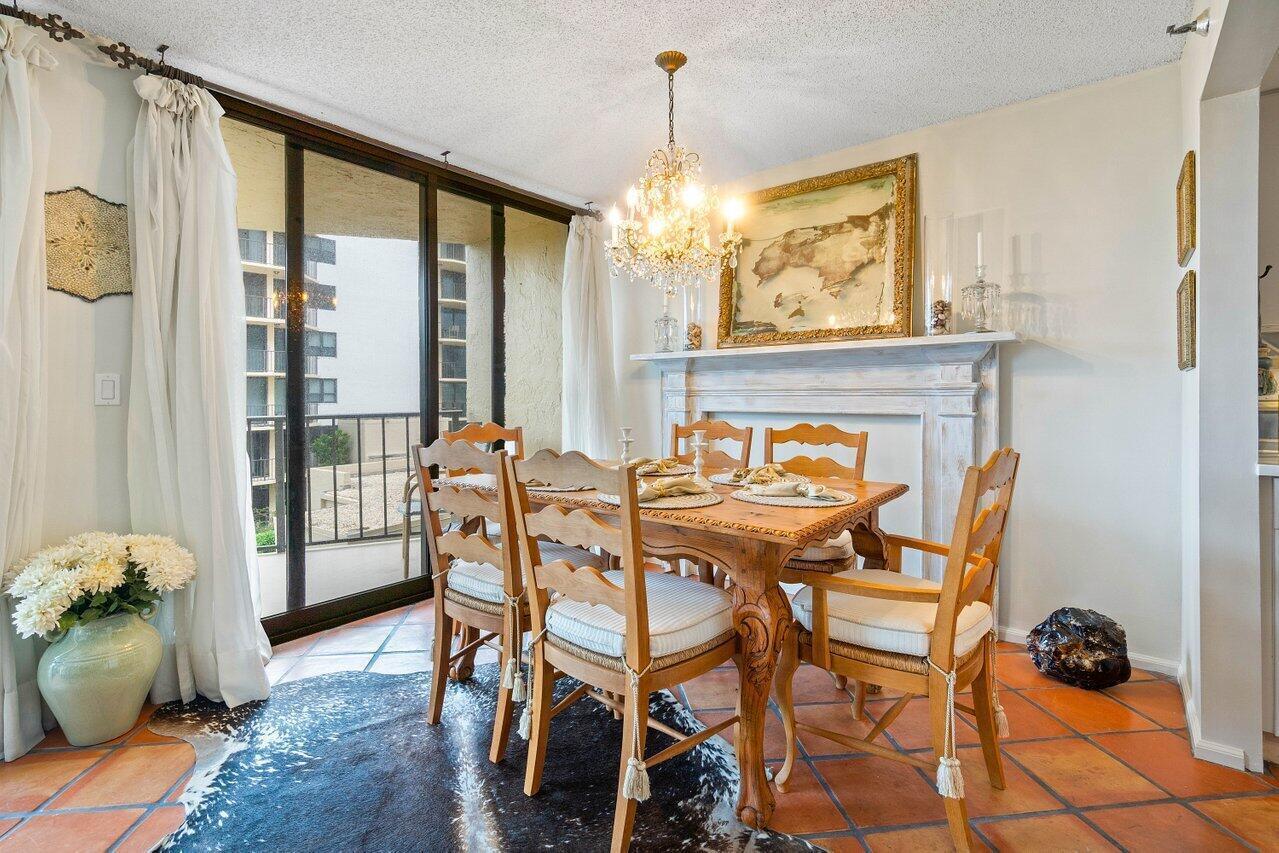 Dining room with a carved wood table, chandelier, tiled floor, and sliding glass doors.