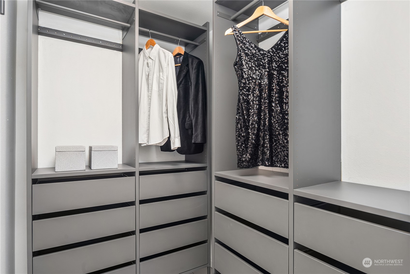 Walk-in closet with gray built-in drawers, hanging clothes, and a sequined dress.