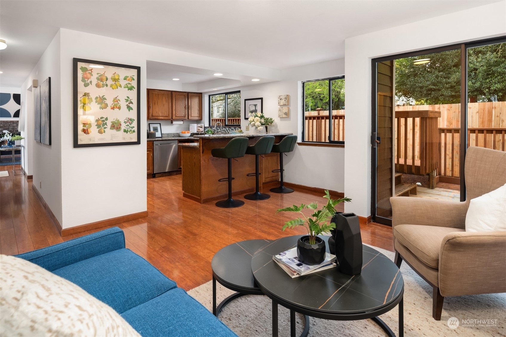 Open living room and kitchen with a wood island, three stools, and sliding doors to a deck.